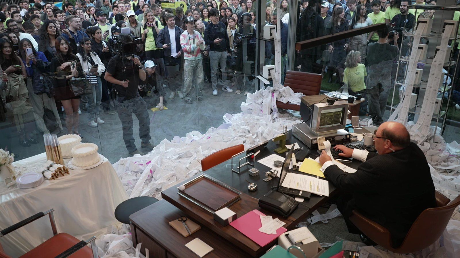 A crowd packed outside the glass office in Flatiron Plaza, receipt strips spooling from the printers